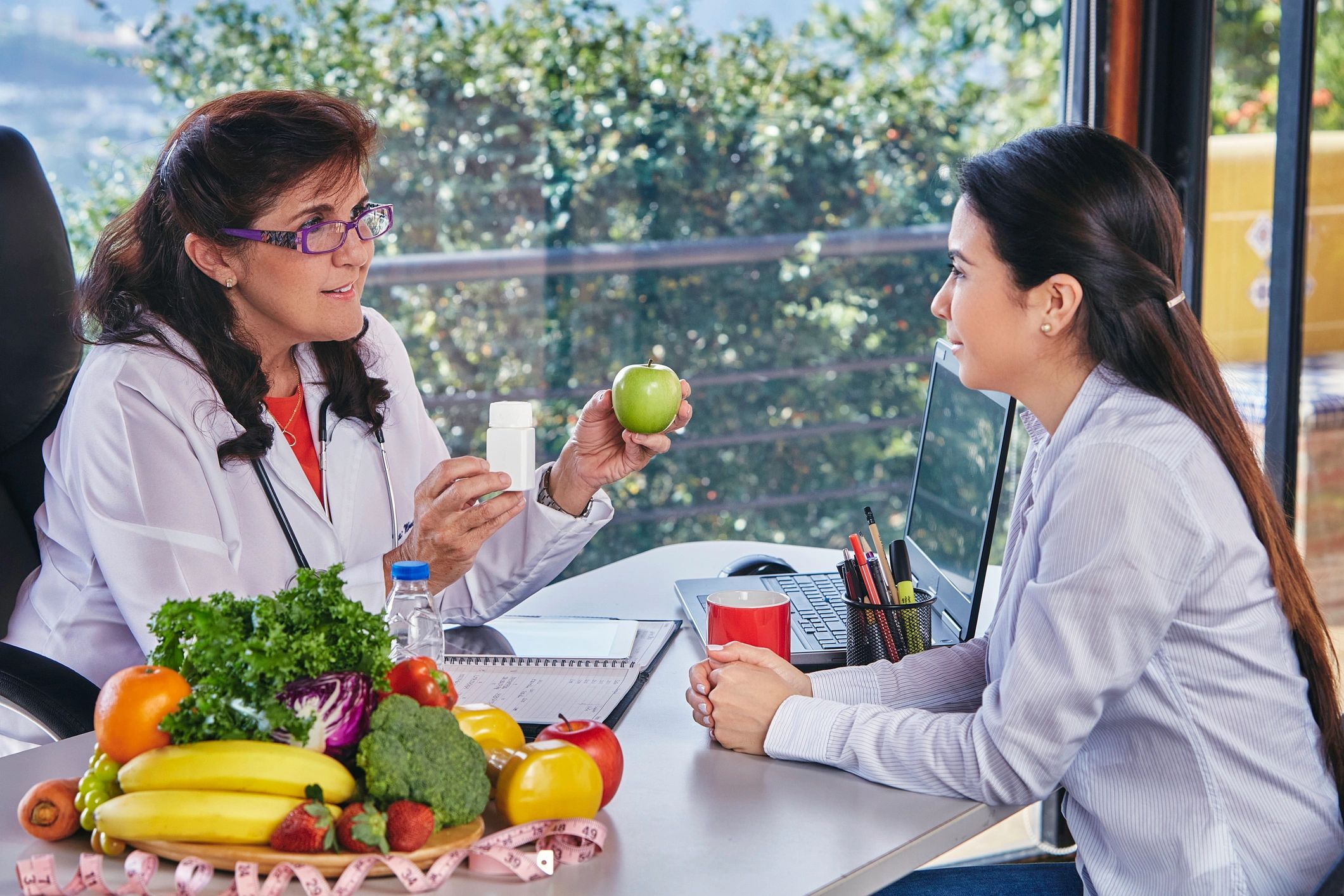 A nutritionist explains healthy eating using an apple and supplement to a client.